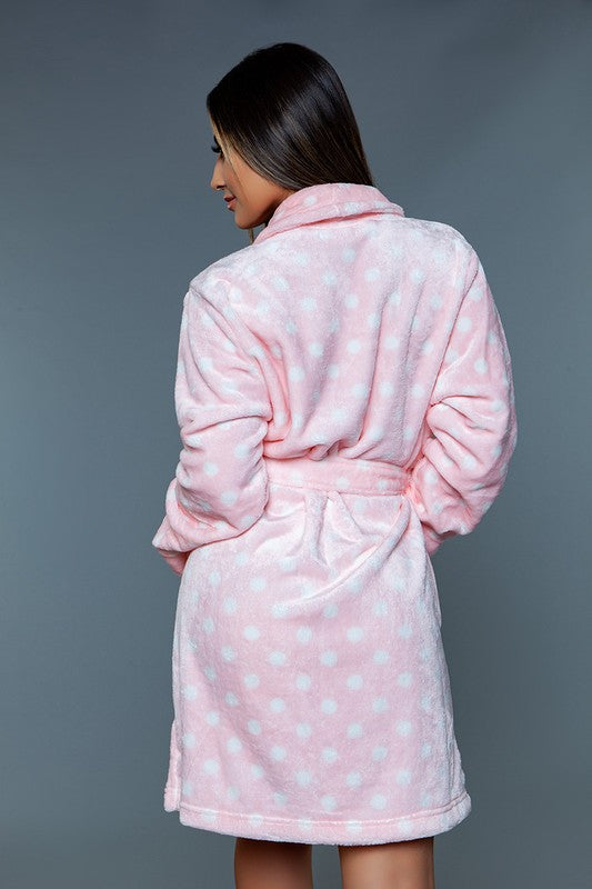 Close-up of a woman wearing a pink polka dot plush robe, showcasing the soft fabric.
