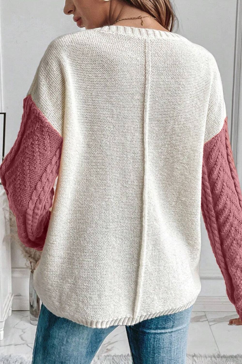 Pink color block cable knit sweater paired with casual outfit.
