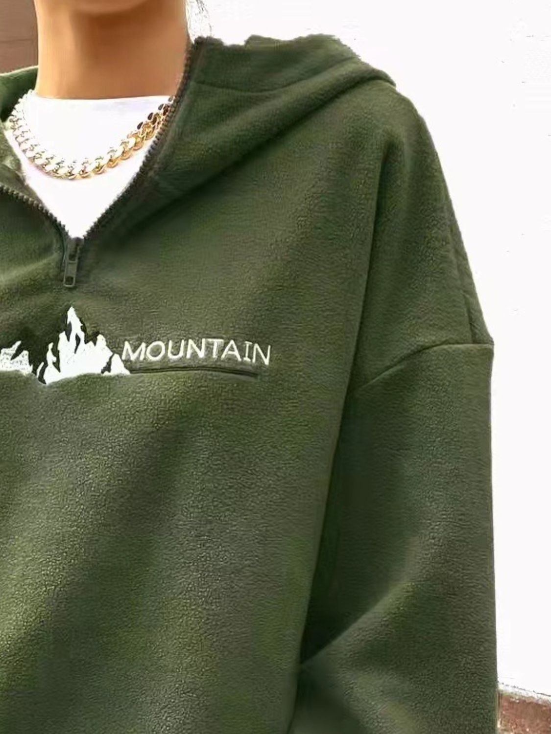 Soft green fleece pullover with mountain graphic and half-zip design.
