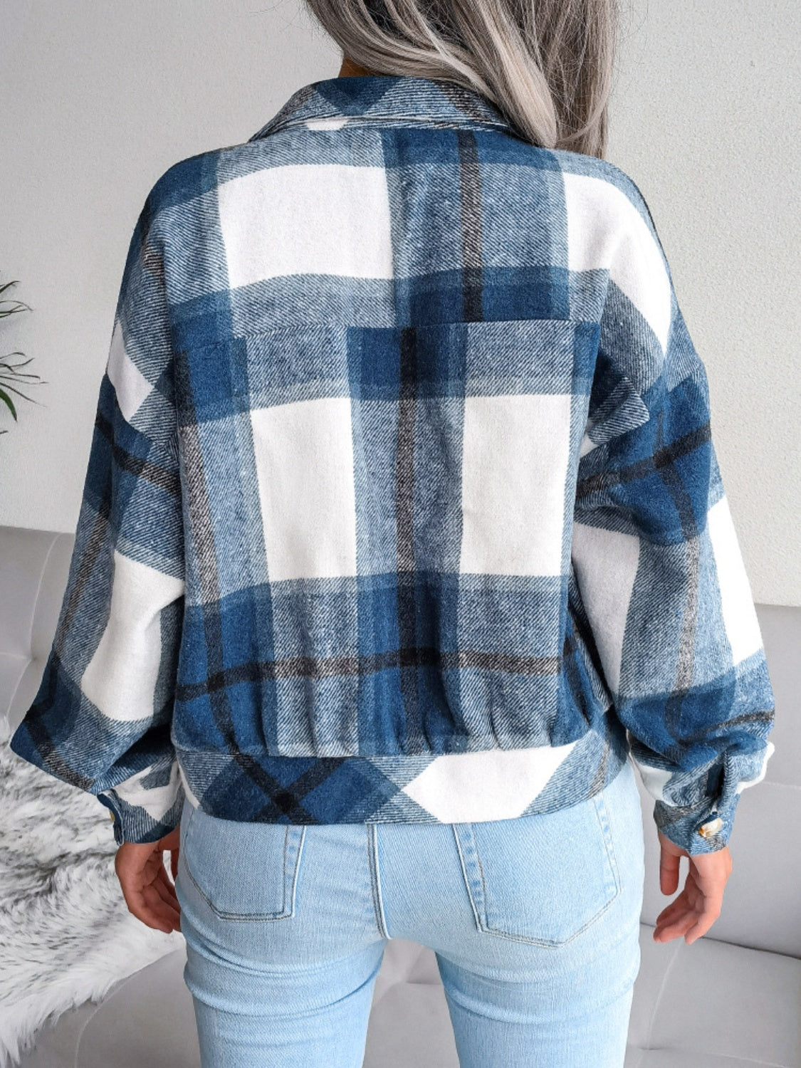 Back view of a blue plaid collared long sleeve jacket for women.
