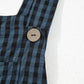 Close-up of wide strap detail and plaid pattern on black wide-leg overalls.
