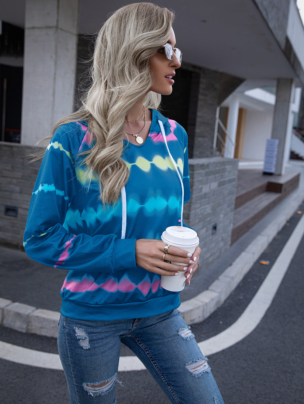 Blue tie-dye hoodie with a relaxed fit and cozy hood, styled with ripped jeans for a casual weekend outfit.
