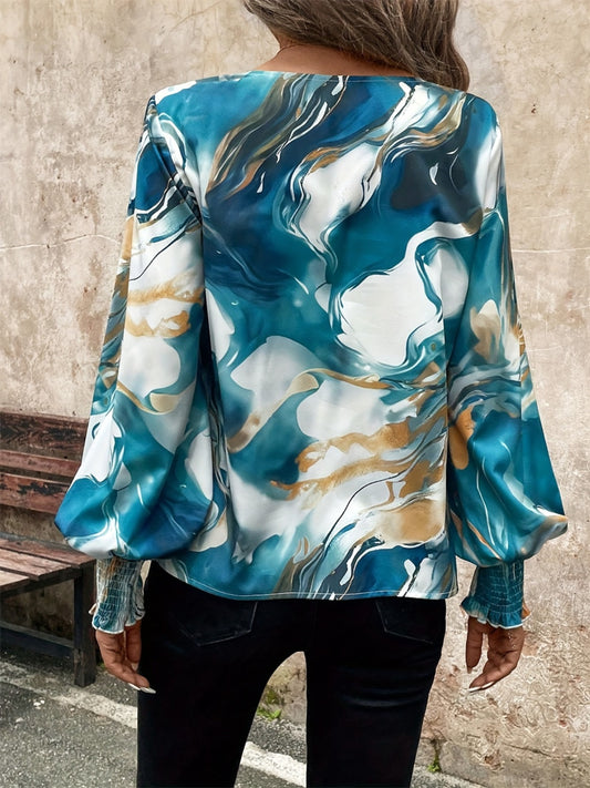 Women’s satin blouse with a vibrant marble print and smocked cuffs, styled for a chic look.
