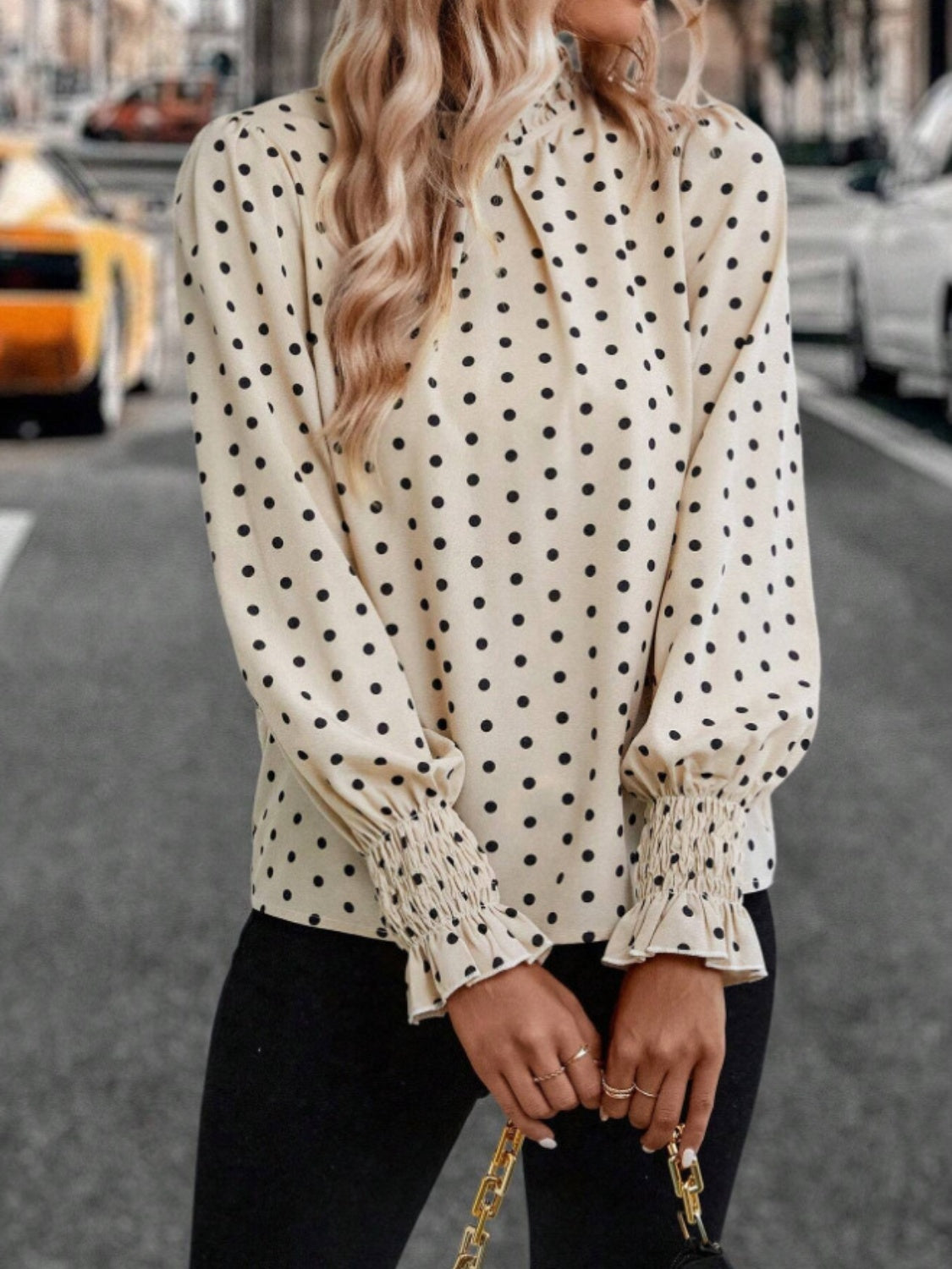 Classic polka dot blouse with feminine ruffled cuffs, styled for a chic, vintage-inspired look.
