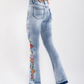 Women's high-rise denim flare jeans with intricate floral embroidery.
