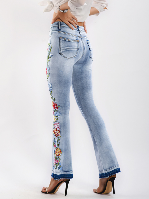 Women's high-rise denim flare jeans with intricate floral embroidery.
