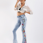 Light wash high-waist denim jeans with colorful floral embroidery.
