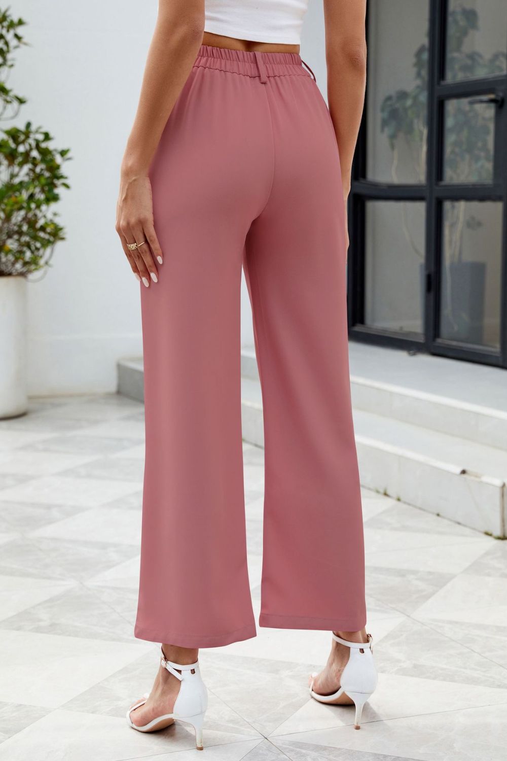 Pink high-waisted trousers styled with a cropped white top
