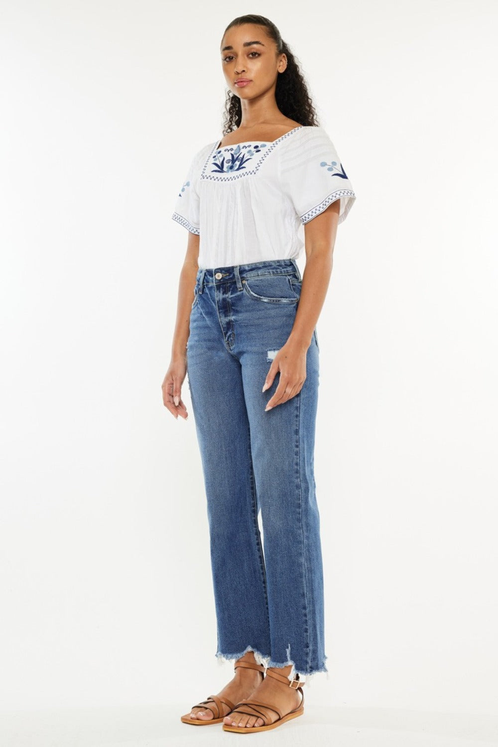 Medium wash Kancan jeans with a high-rise fit, wide leg, and raw hem, perfect for casual styling.
