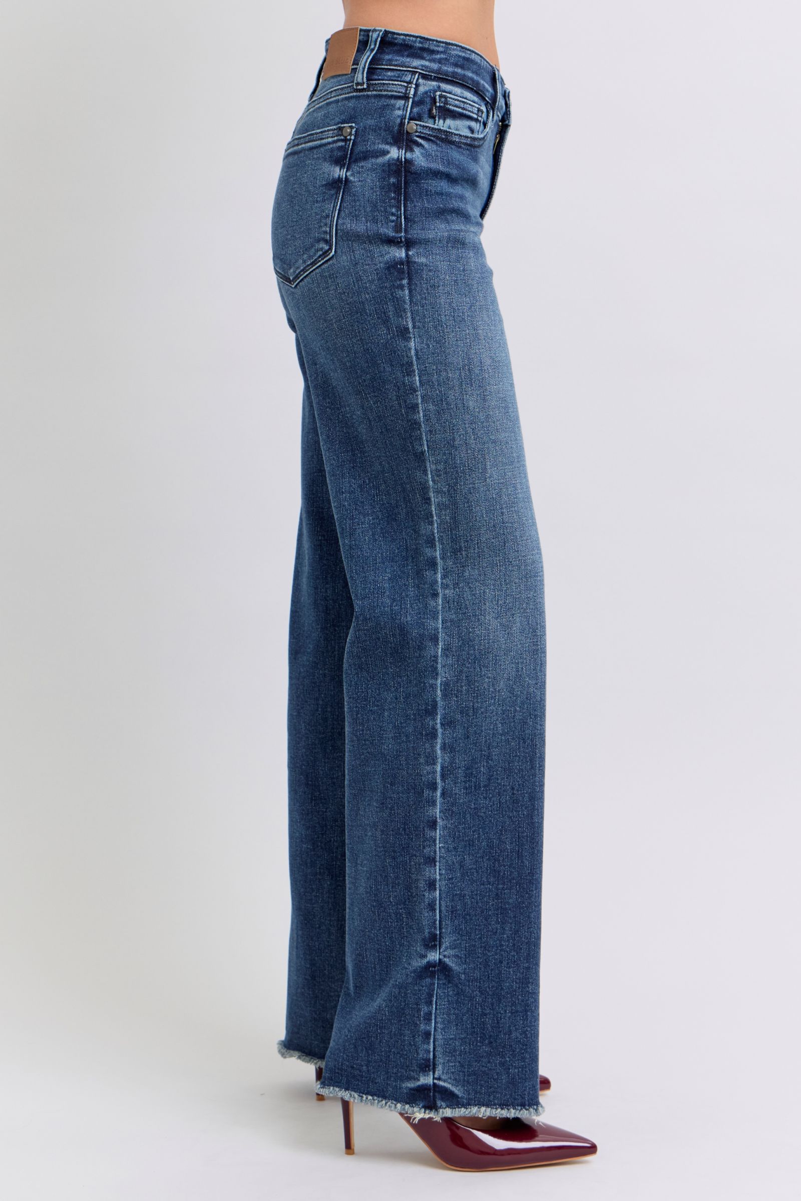 Medium wash raw hem jeans styled with red heels
