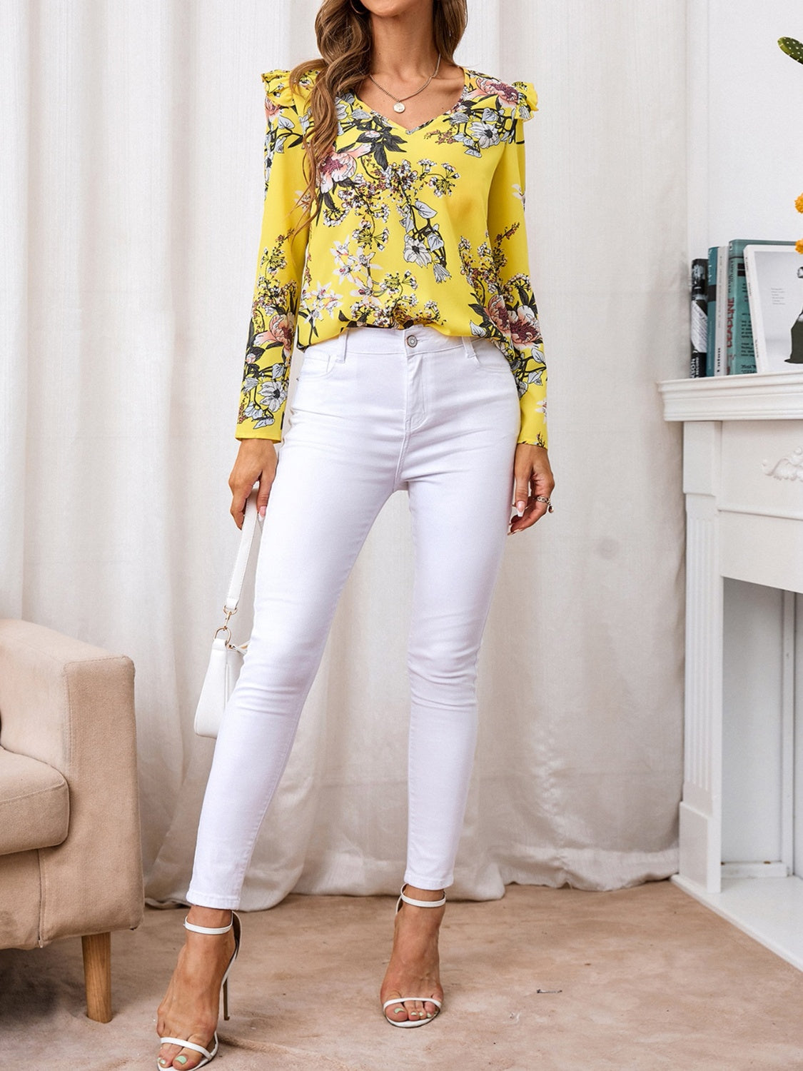 Bright yellow blouse with floral print and ruffled shoulders, styled with white jeans and a casual purse.
