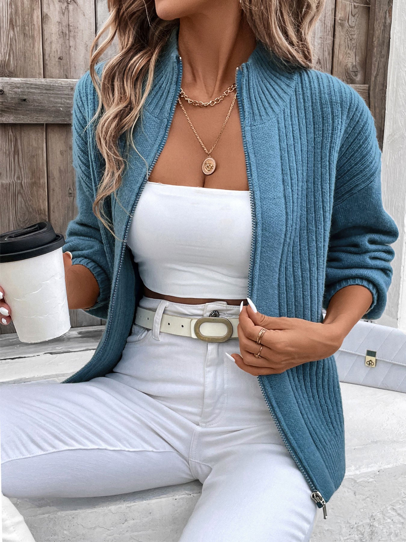 Woman wearing blue ribbed zip-up cardigan with moderate stretch.
